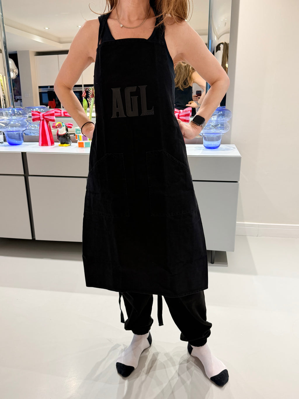Person wearing a personalised black apron with a brand logo.