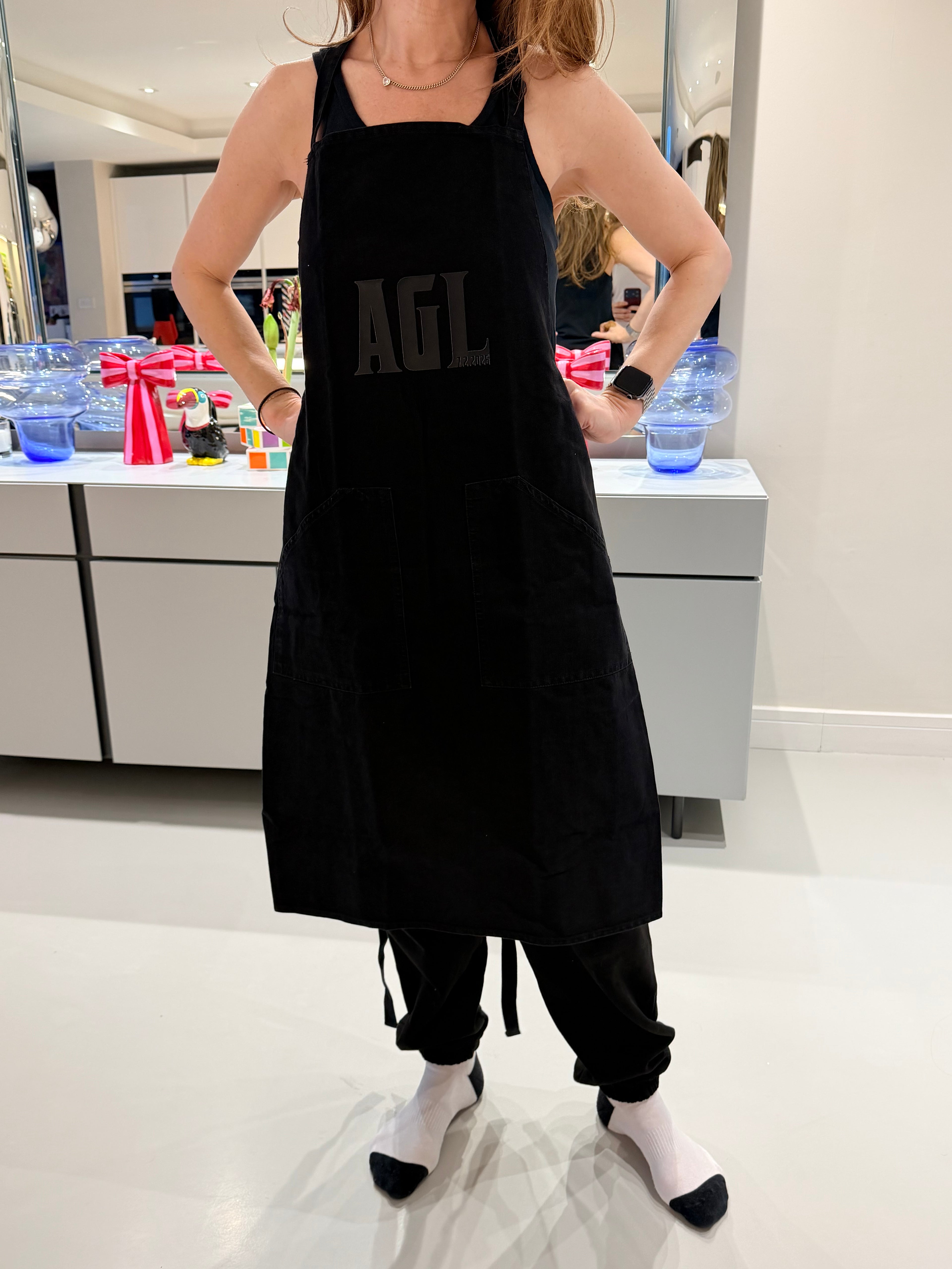 Person wearing a personalised black apron with a brand logo.
