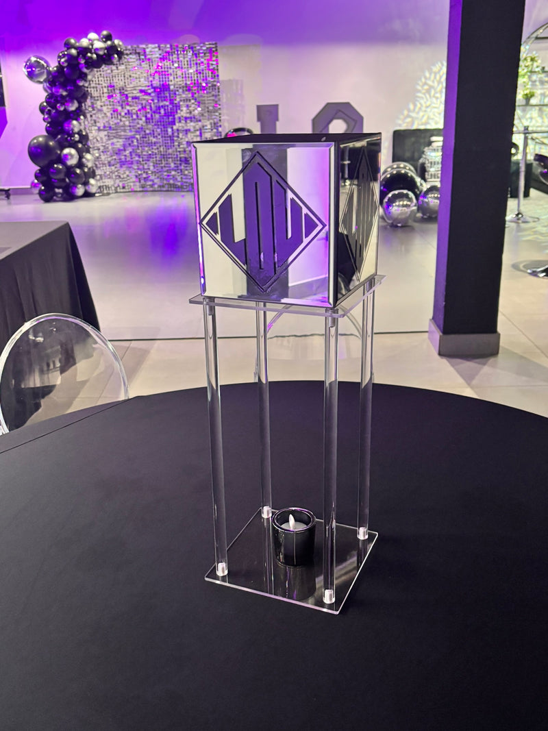 Clear acrylic gift card box podium with decorative elements in a room with purple lighting