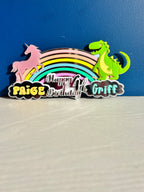 Colorful birthday acrylic cake topper with unicorn, rainbow, and dinosaur on a blue background