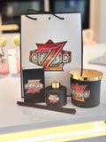 Diffuser with gold accents and a decorative bag featuring a logo and matchbox gift set