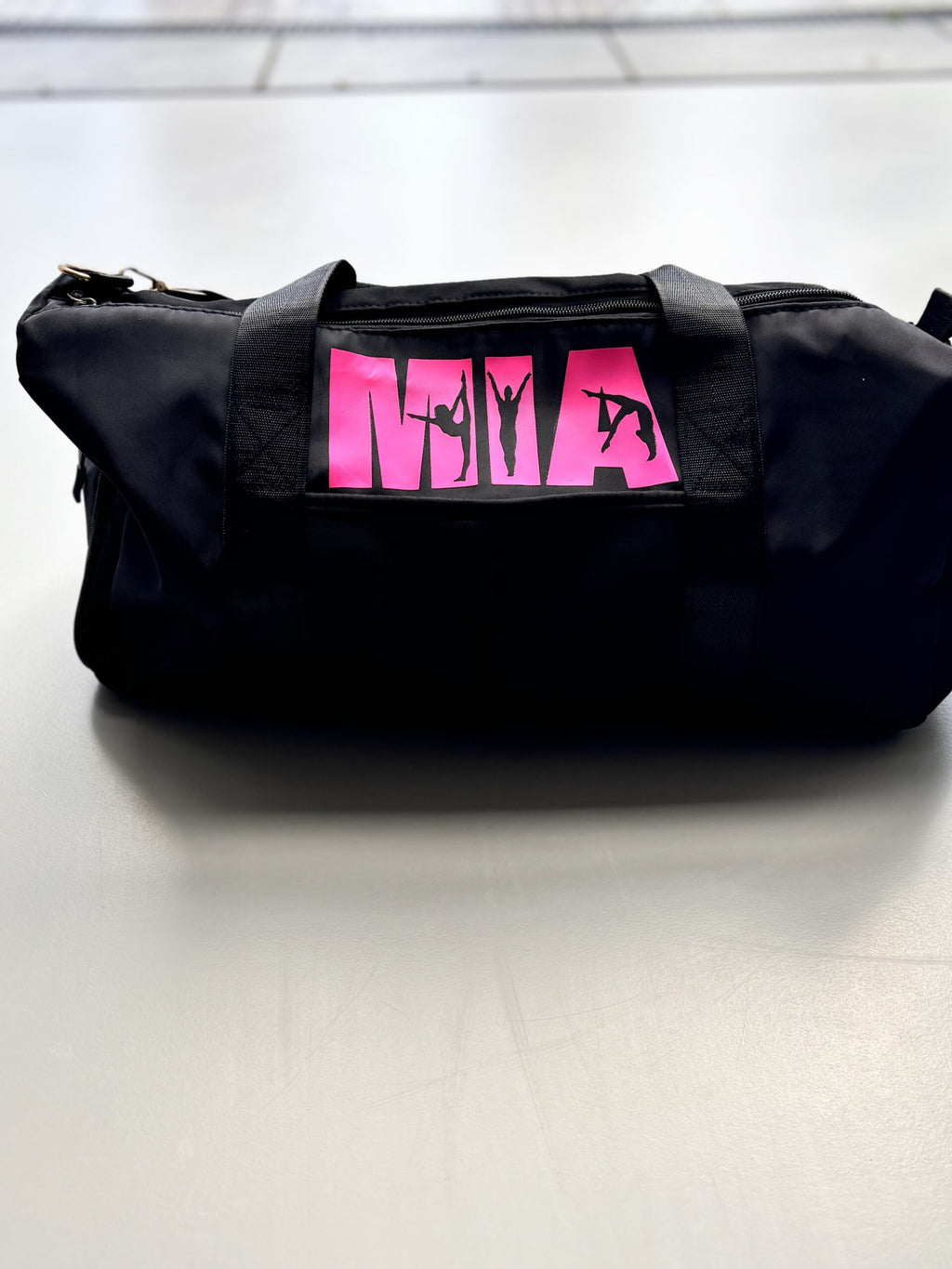 Black washbag with pink logo on a tiled floor