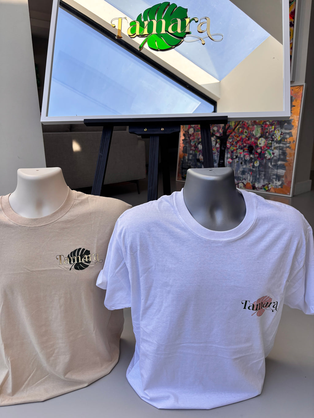 White and beige event t-shirt with a logo on a table next to a computer screen