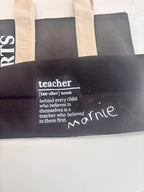 Personalised black tote bag with 'teacher' definition text on a white background