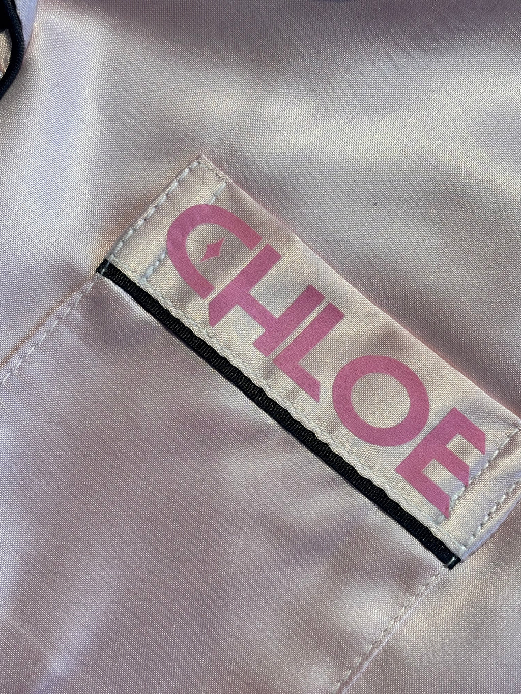 Label with 'CHLOE' printed on a beige pyjama front pocket 
