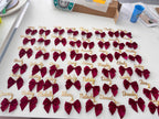 Maroon bow keyrings with names on a white surface