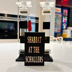 Decorative match box sleeves with a sign reading 'Shabbat at the Schallers' in a store setting.