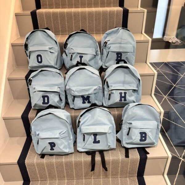 Multiple grey backpacks with letters on a staircase
