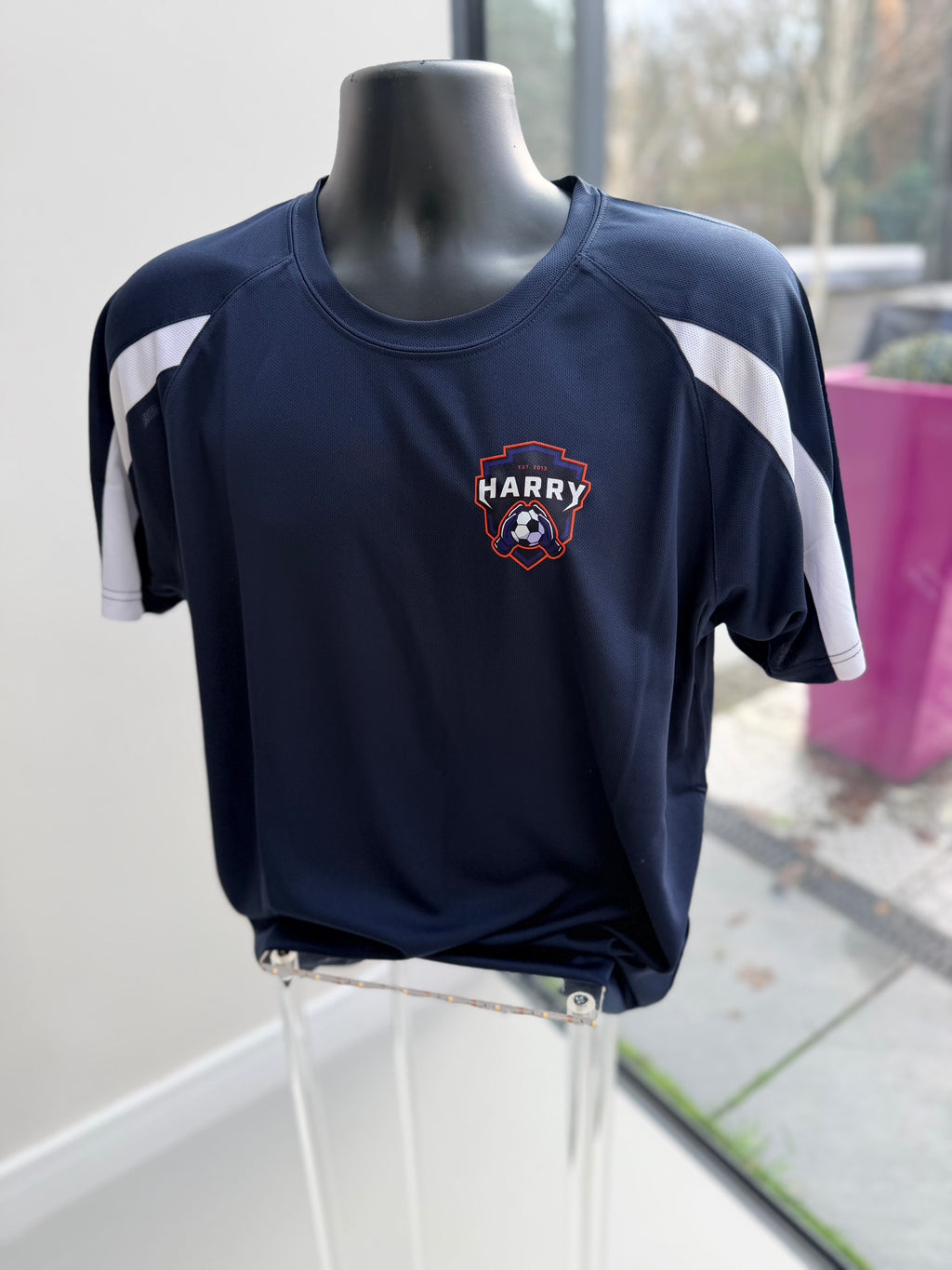 Navy football top with 'Harry' logo on a mannequin in front of a window.
