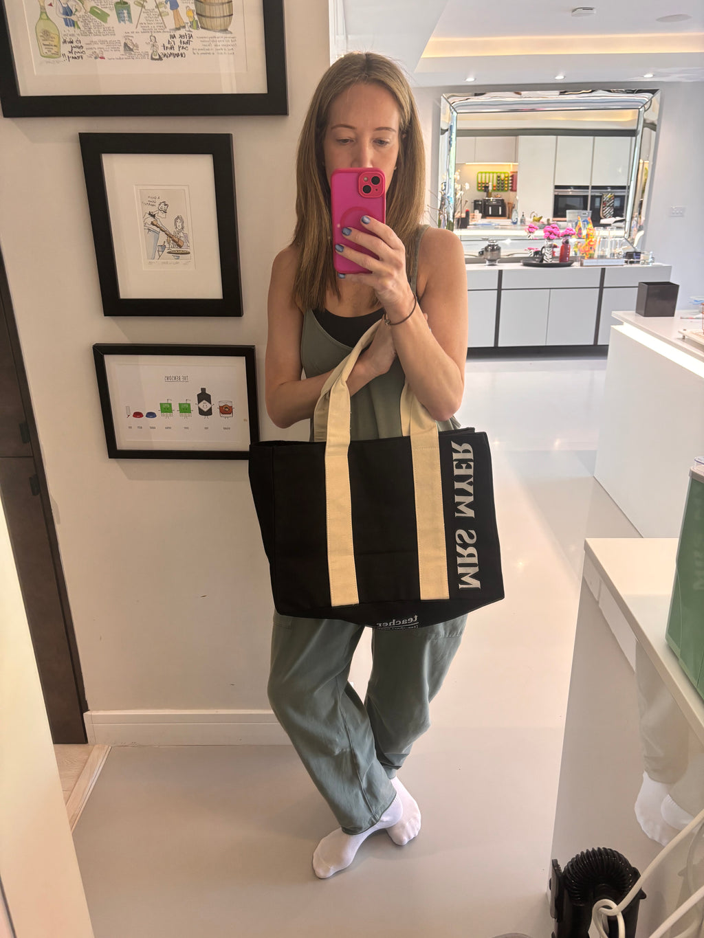 Person holding a black and beige tote bag with 'MRS MYER' branding in a home setting.