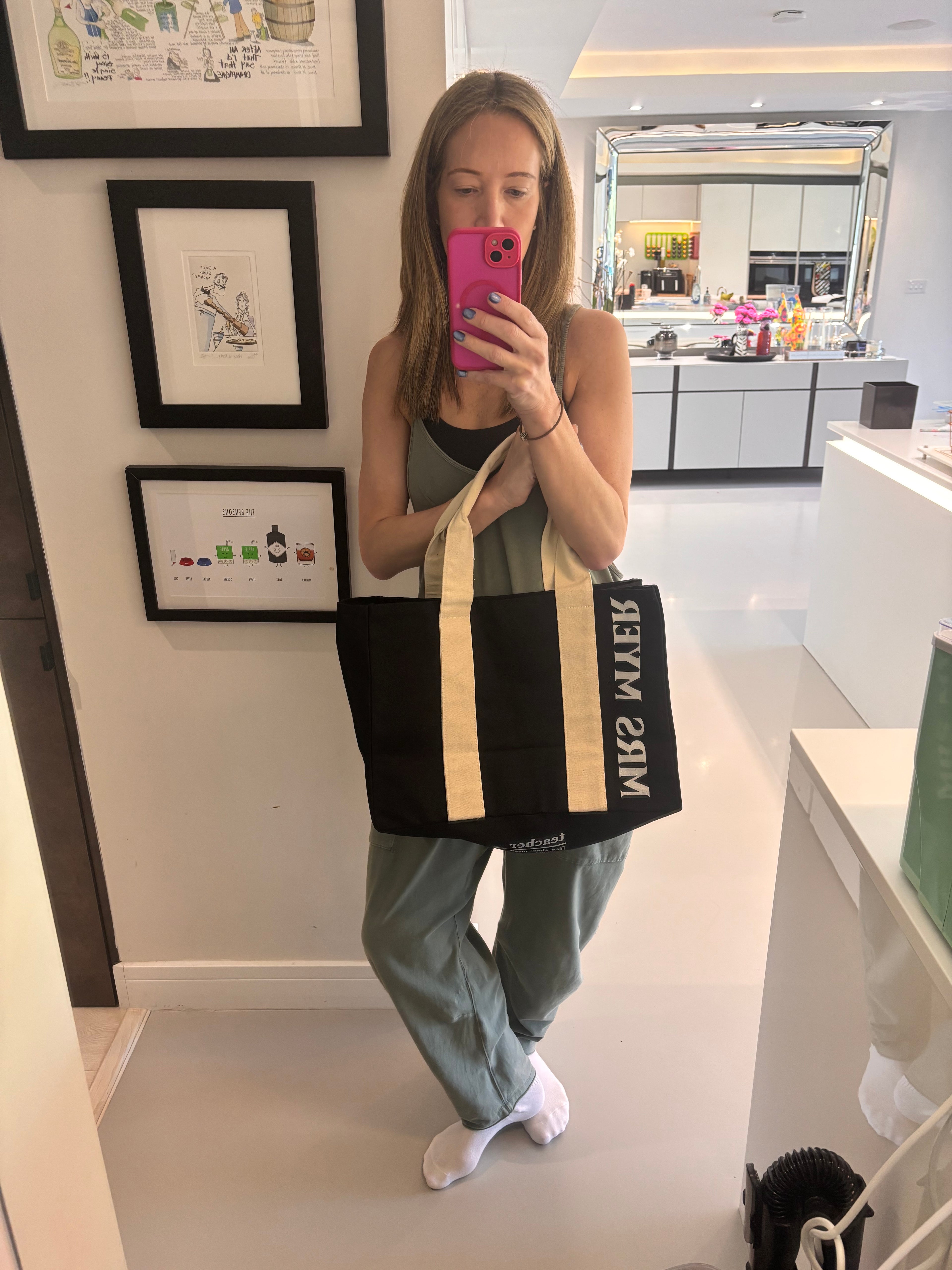 Person holding a black and beige tote bag with 'MRS MYER' branding in a home setting.