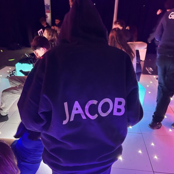 Person wearing a hoodie with 'JACOB' printed on the back in a social setting.