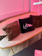 Pink chair with leopard print logo pillows and a black pillow with pink text.