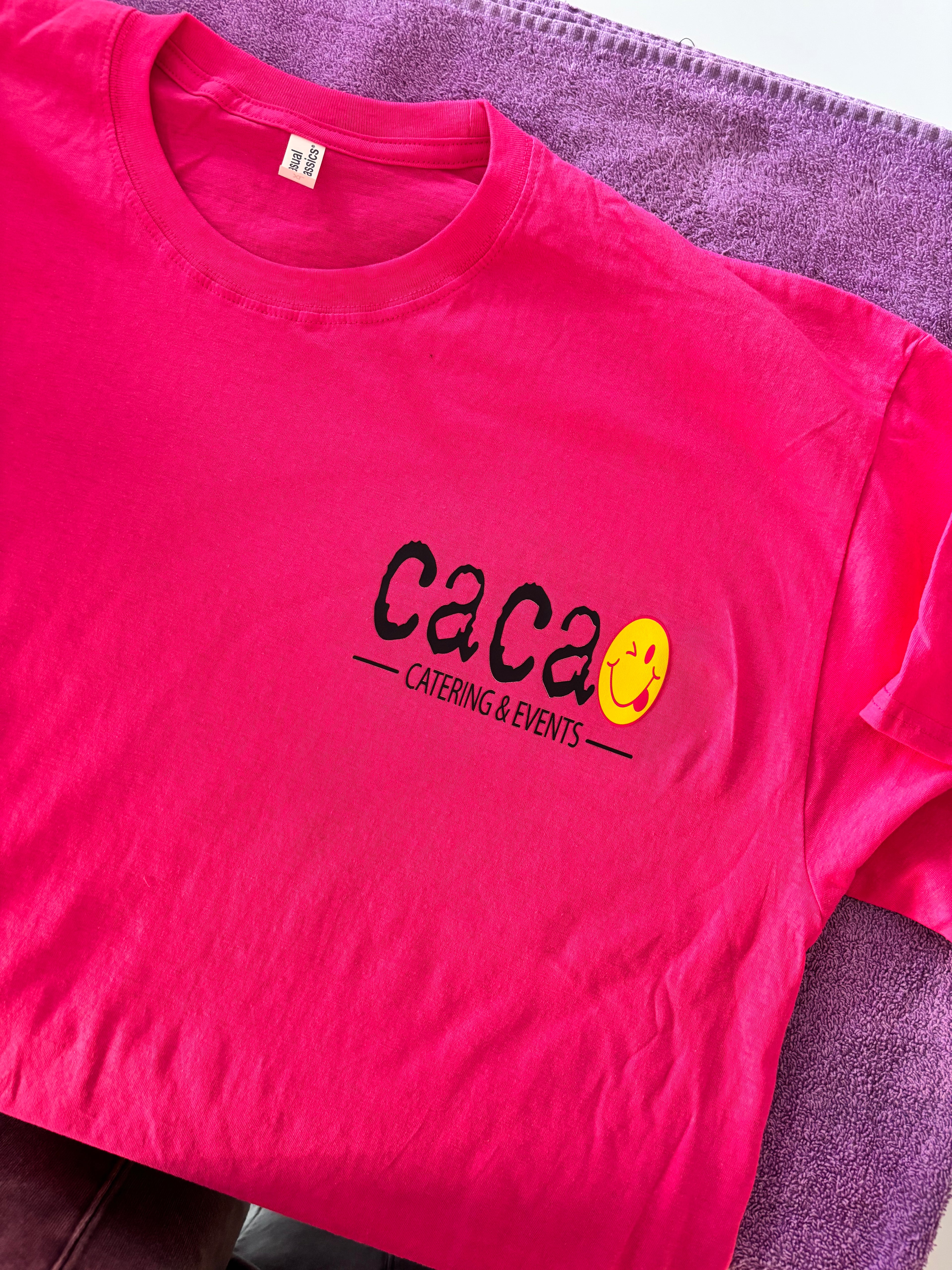 Pink event t-shirt with 'Caca' logo on a purple surface