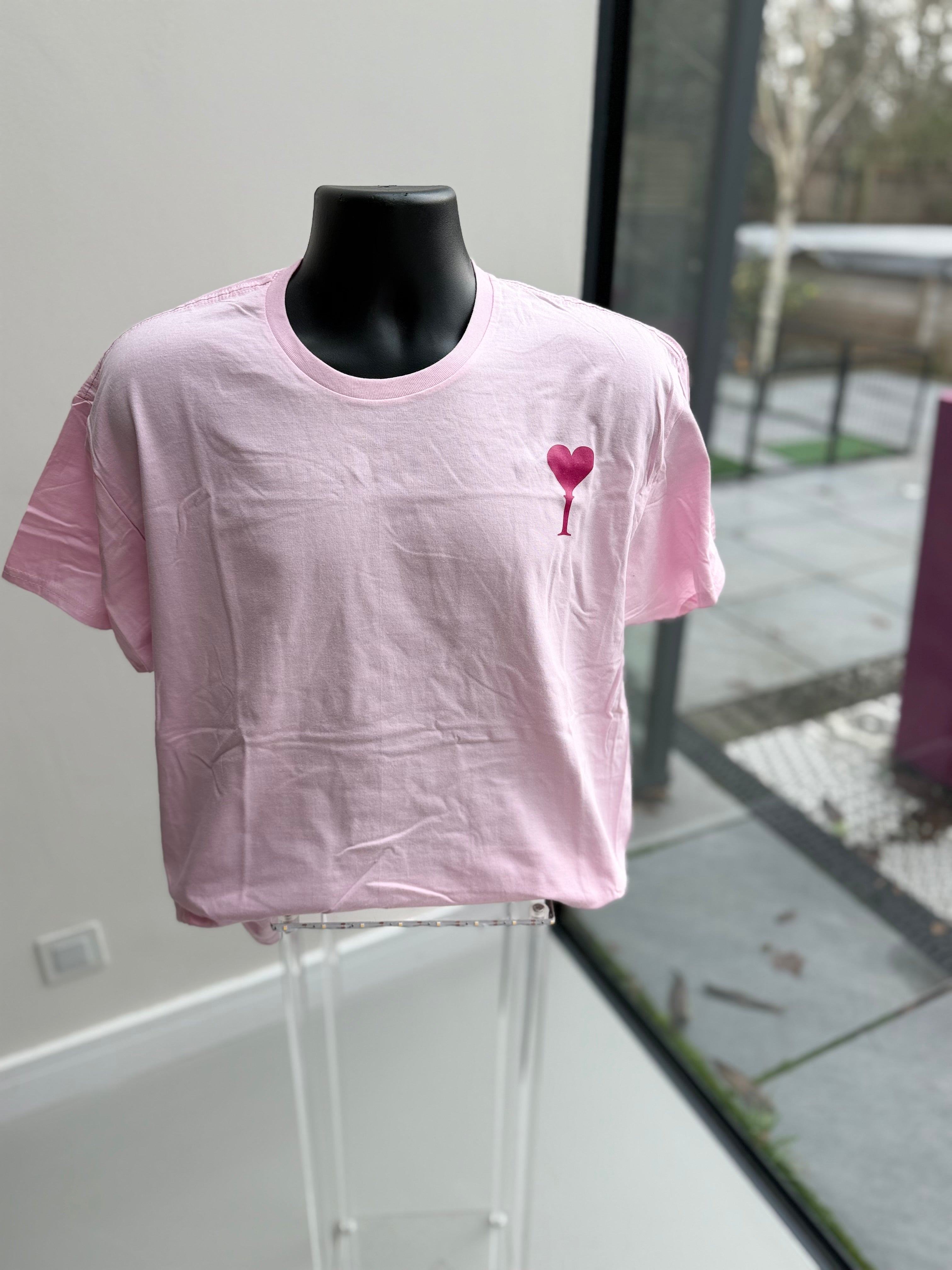 Pink event t-shirt with a heart design on a mannequin against a glass door background