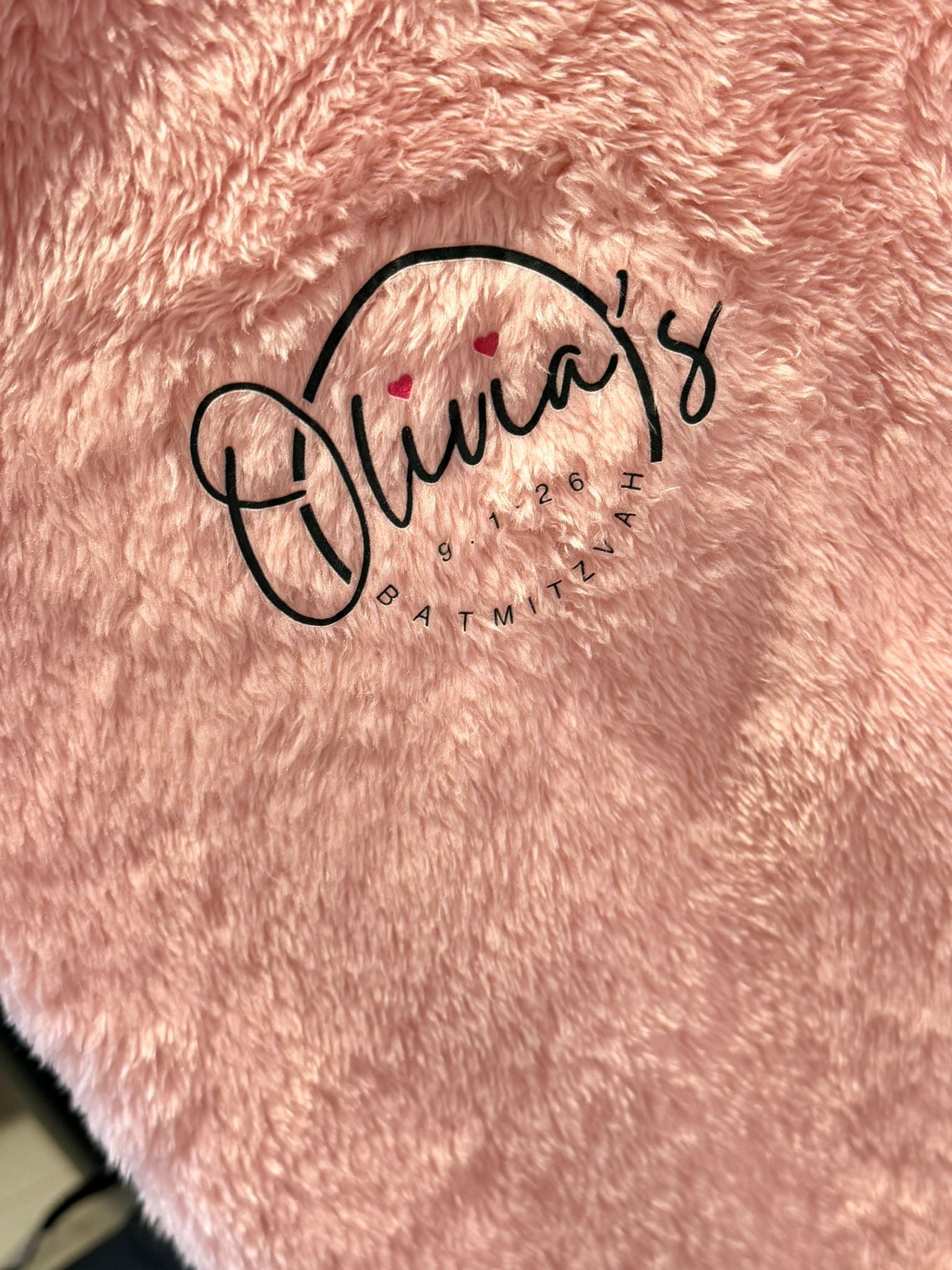 Pink fluffy pyjamas bottoms with 'Olivia's Bat Mitzvah' text embroidered on it.
