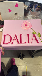 Pink keepsake box with 'DALIA' branding on a cluttered surface