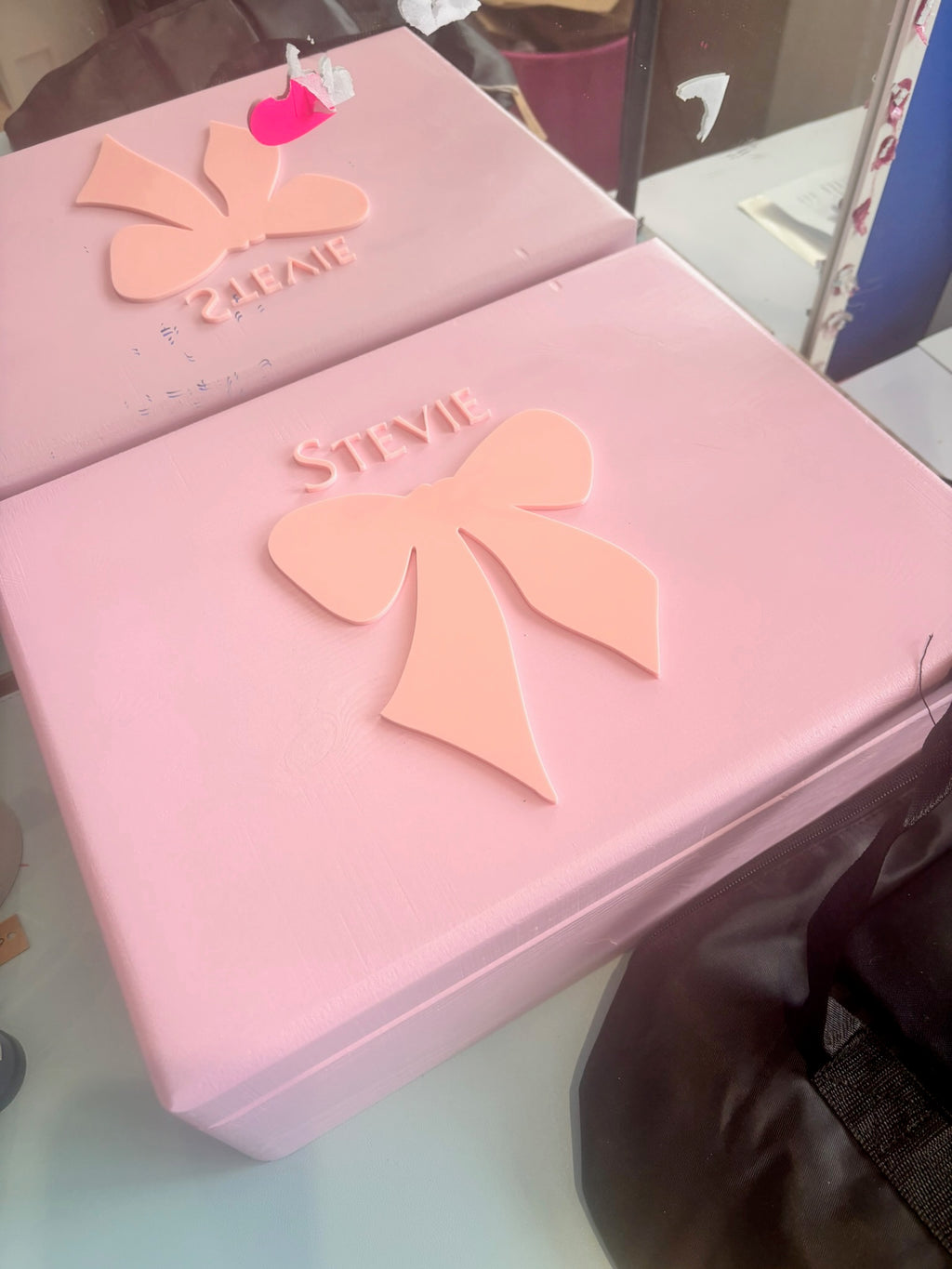 Pink keepsake box with a bow design and 'Stevie' branding on a reflective surface.