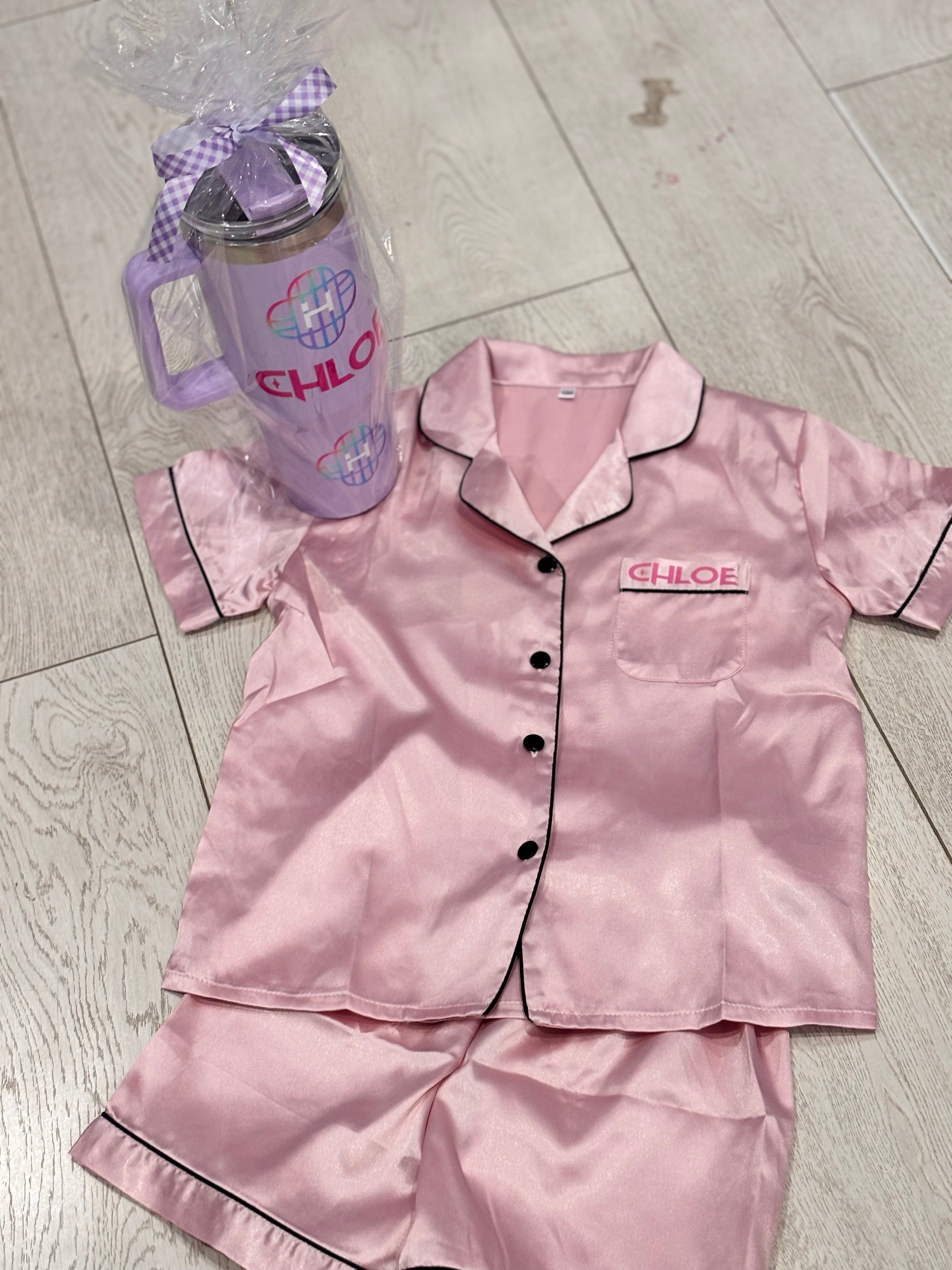 Pink pyjamas set with 'Chloe' branding and a matching water bottle on a tiled floor.