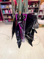 Purple lip gloss keyrings with silver cap on a reflective surface, blurred background