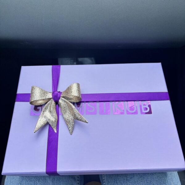 Purple personalised games gift box with a gold bow on a car seat