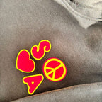 Red and yellow 'SOS' symbol with a peace sign on grey hoodie