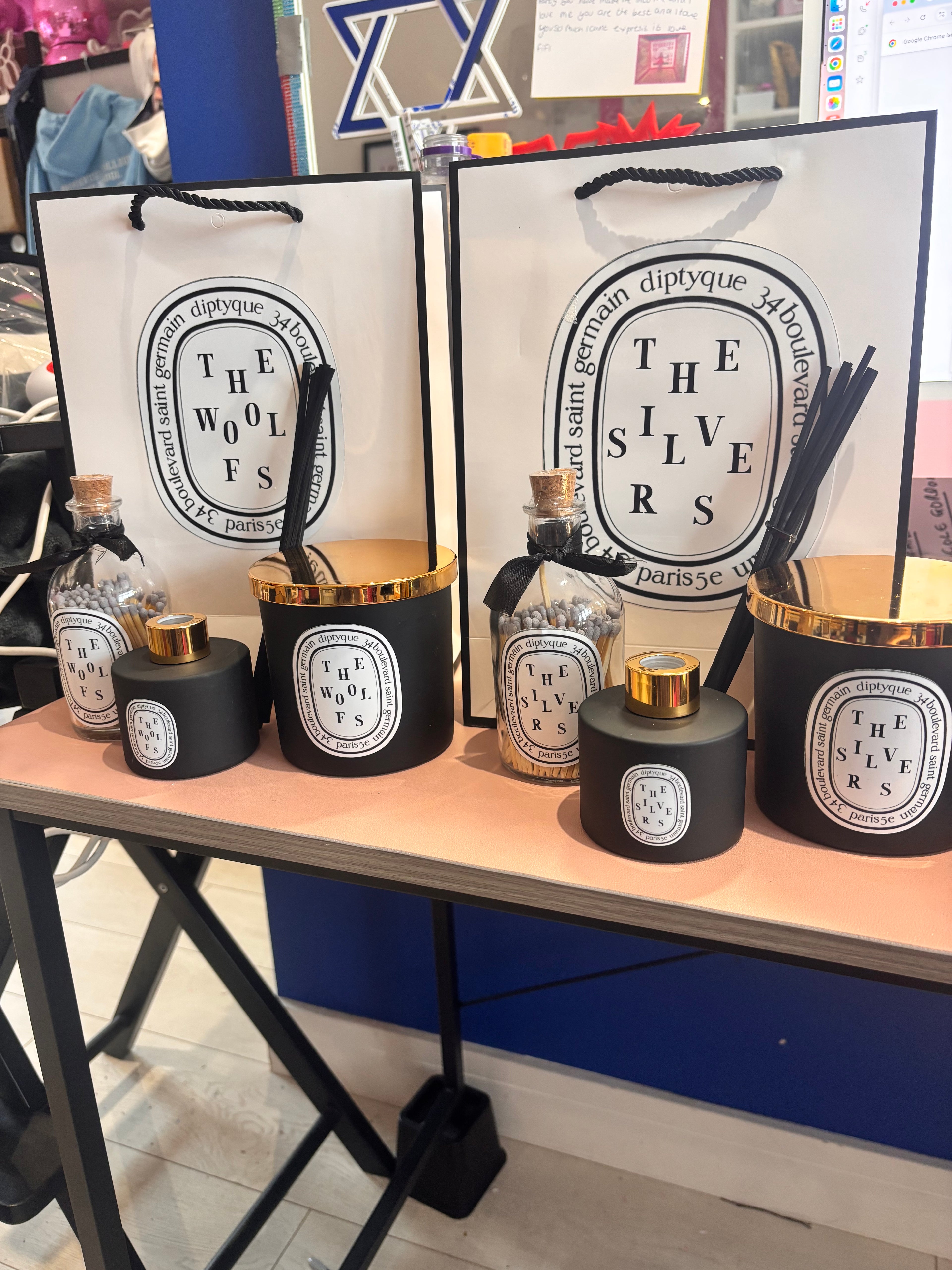 Set of personalised candle, match bottle and diffuser sets with decorative boxes on a stand