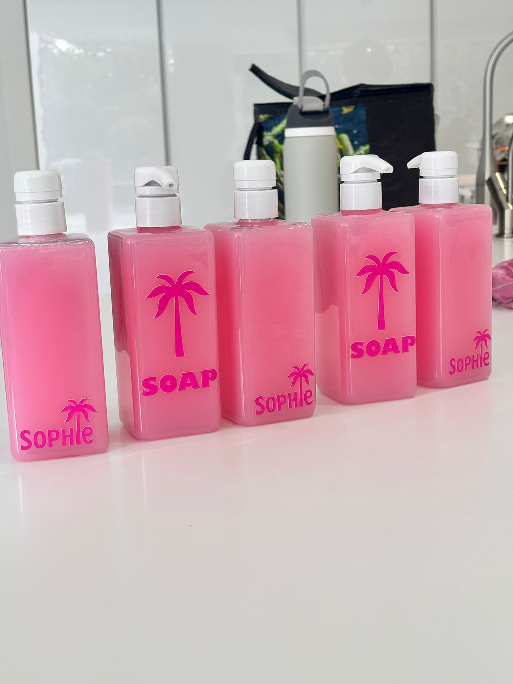Set of pink soap bottles with 'Sophie' branding on a white background