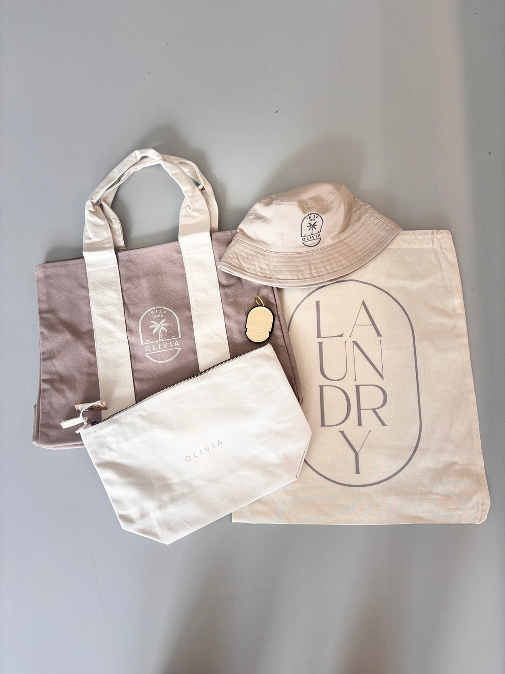 Set of three personalised tote bags including a tote, a hat, and a laundry bag on a grey background