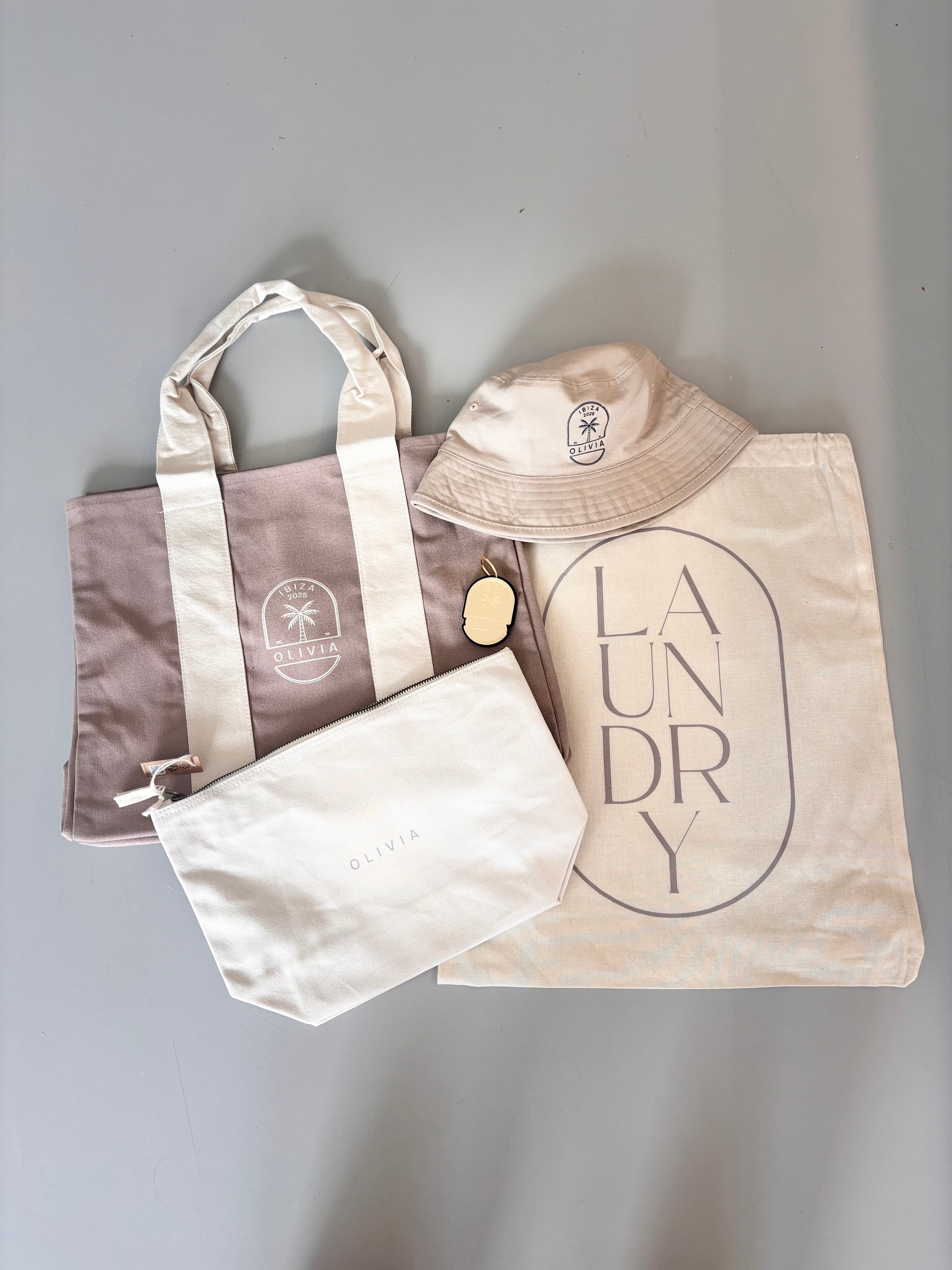 Set of three personalised tote bags including a tote, a hat, and a laundry bag on a grey background