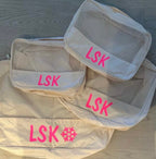 Set of white packing cubes with 'LSK' branding in neon pink.
