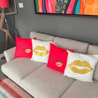 Grey sofa with decorative personalised silk pillow cases featuring names and gold lip prints in a living room setting.