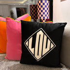 Silk pillow case with a black pillow featuring a geometric design on a couch.