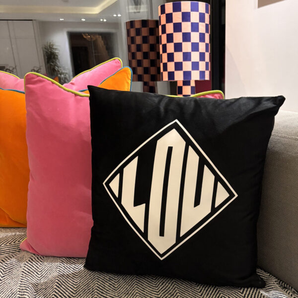 Silk pillow case with a black pillow featuring a geometric design on a couch.
