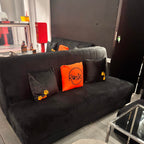 Black sofa with decorative personalised silk pillow case in a room setting with dog paw print designs.