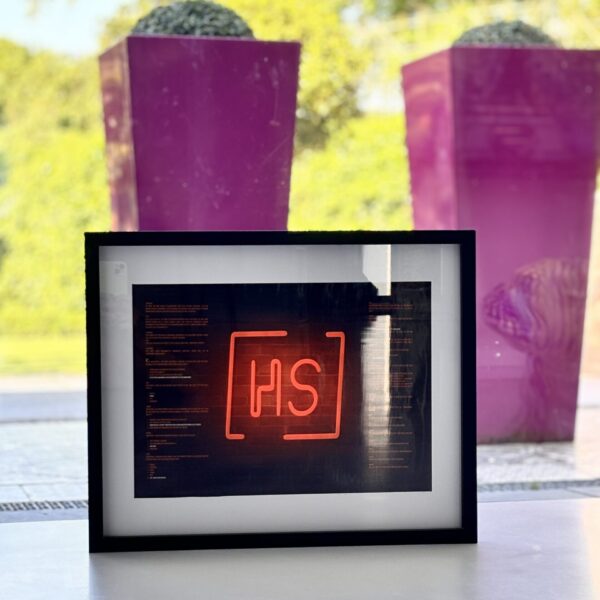 Framed speech gift with red 'HS' logo on a blurred background with acrylic