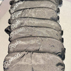 Stack of black sleep masks with names printed on them against a white background.