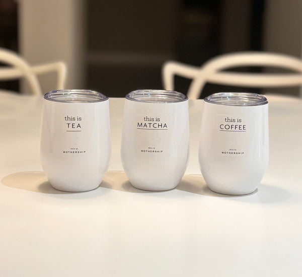 Three white travel cups labelled 'this is TEA', 'this is MATCHA', and 'this is COFFEE' on a light surface.