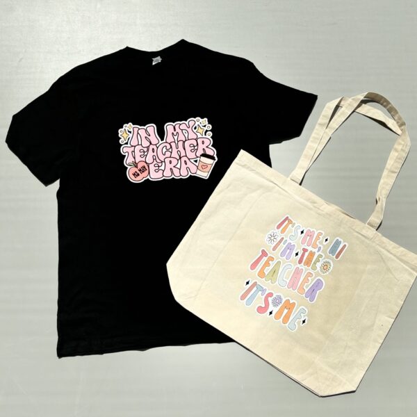 Black t-shirt and beige tote bag with colourful text design on a grey background