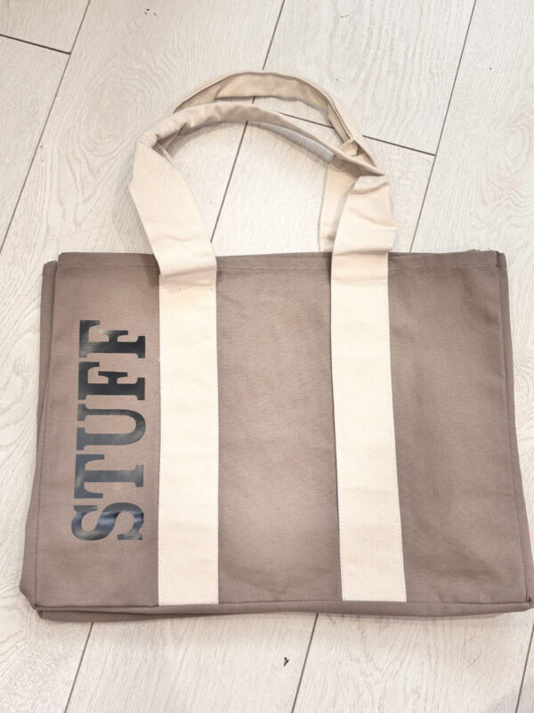 Tote bag with 'STUFF' printed on it on a light wooden floor.