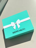 Turquoise keepsake box with white ribbon and 'SIENNA & CO.' branding on a light grey background