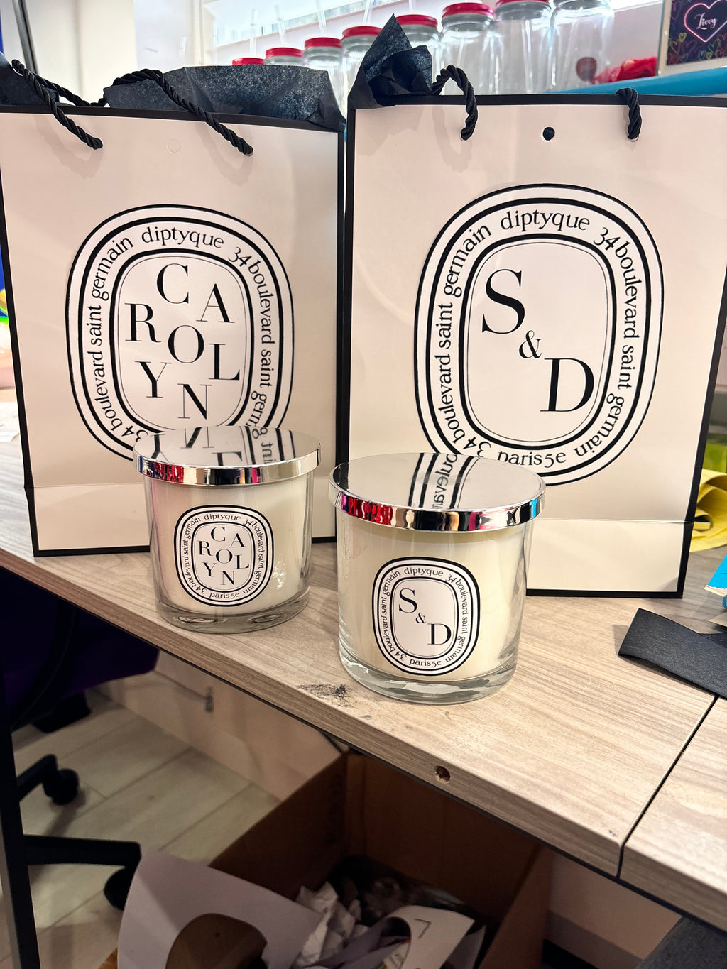 Two Diptyque-style candles on a wooden surface with visible branding.