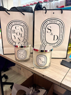 Two Diptyque-style candles on a wooden surface with visible branding.