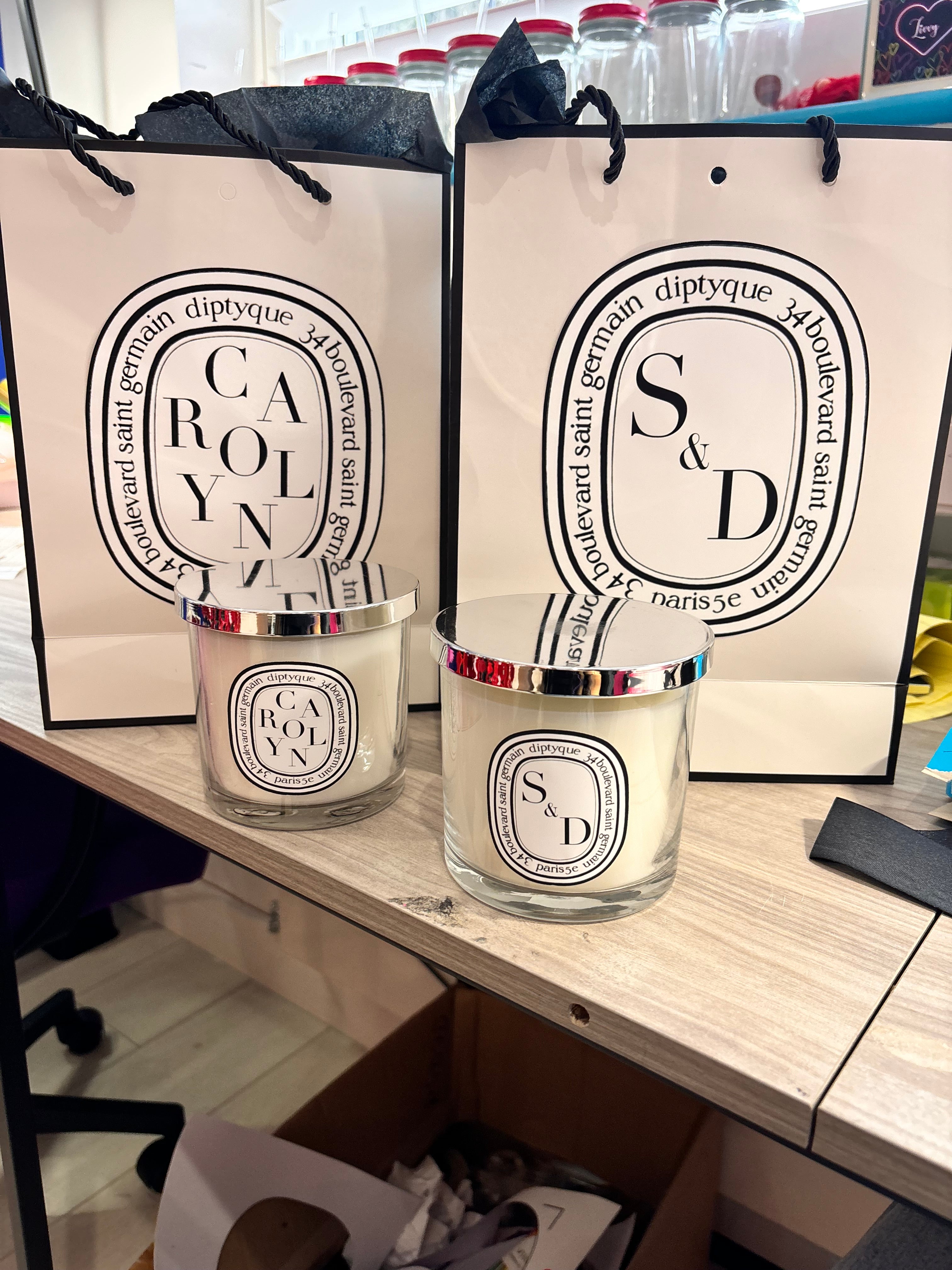 Two Diptyque-style candles on a wooden surface with visible branding.