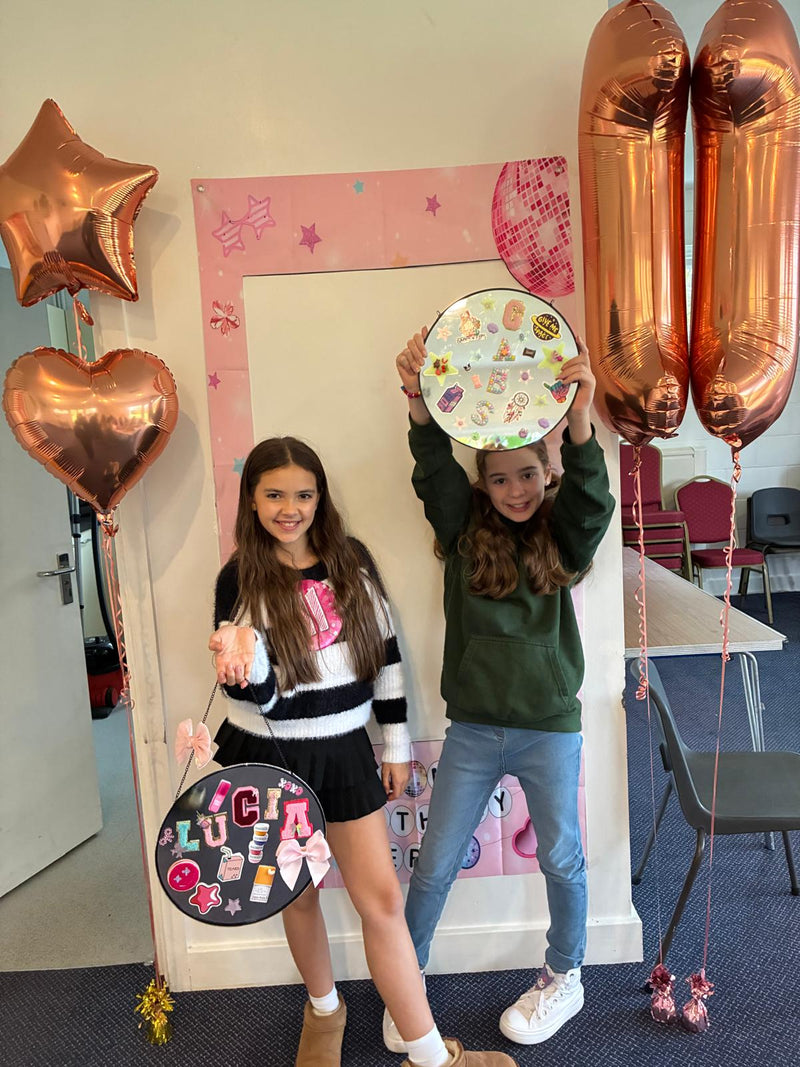 Two children holding decorative mirrors with balloons and a pink frame in the background from a Mirrored Memories mirror party