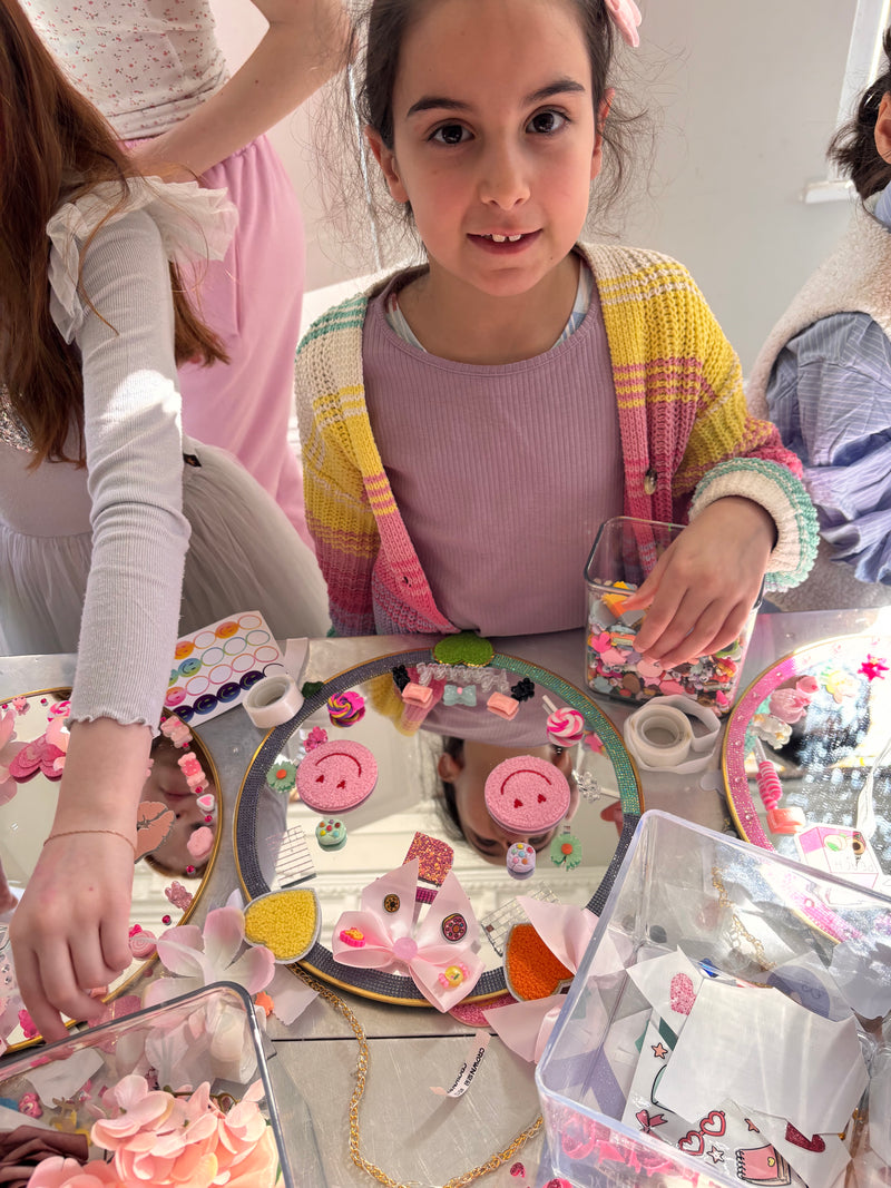 Two children playing with decorative mirrors on a table taken at a Mirrored Memories mirror party