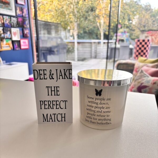 Two decorative candles on a table with 'DEE & JAKE THE PERFECT MATCH' and a motivational quote.