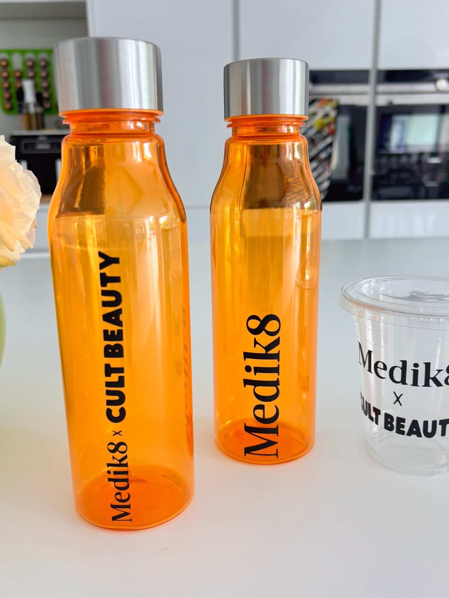 Two orange sports insulated water bottles with silver lids on a white surface, featuring 'Medik8' branding.