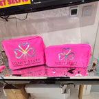 Two pink washbags with 'Toni's Stuff' logo on a reflective surface.