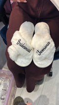 White slippers with 'Jewelry' and 'Bridesmaid' text held by a person in a maroon garment